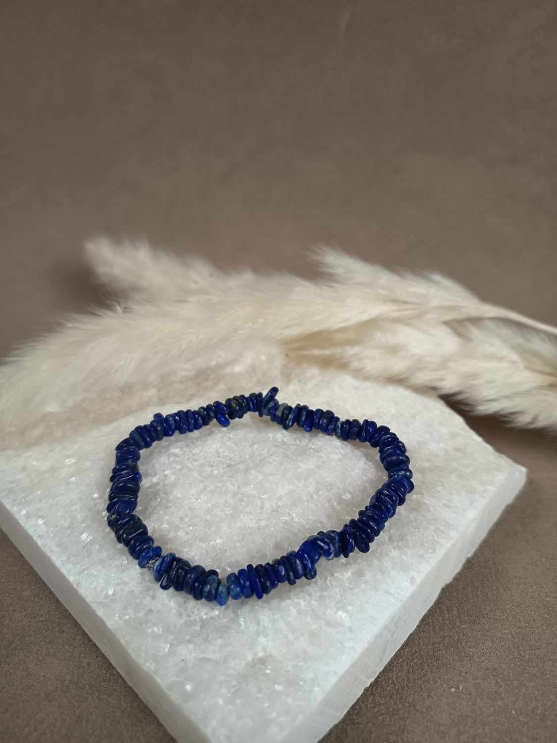 Lumara Lapislazuli Splitterarmband auf weißem Kristallsockel – handgemachtes Heilsteinarmband für Intuition, Wahrheit und innere Klarheit