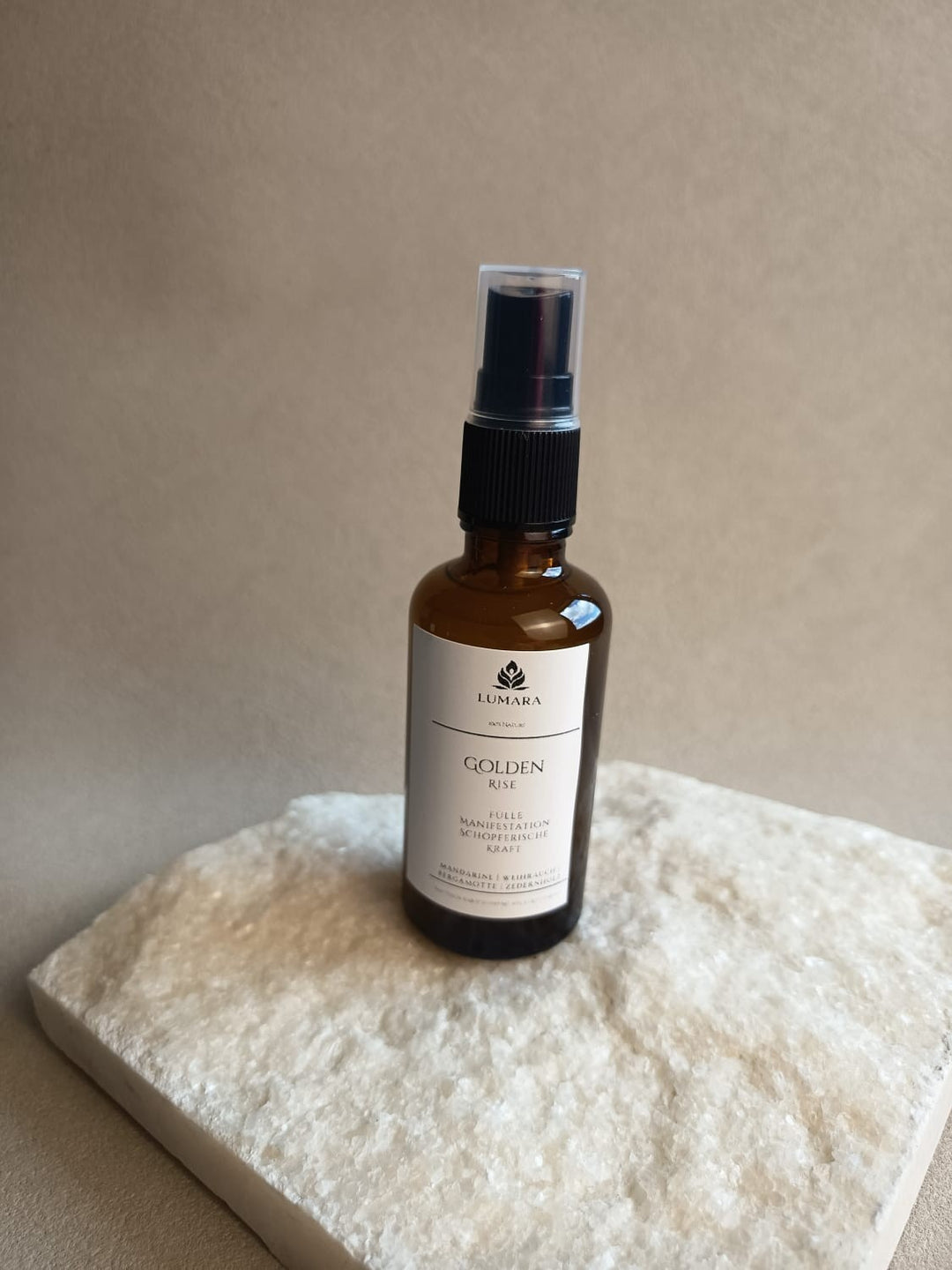LUMARA Golden Rise Beltane Aura Spray in Amber Glasflasche auf hellem Stein dekoriert