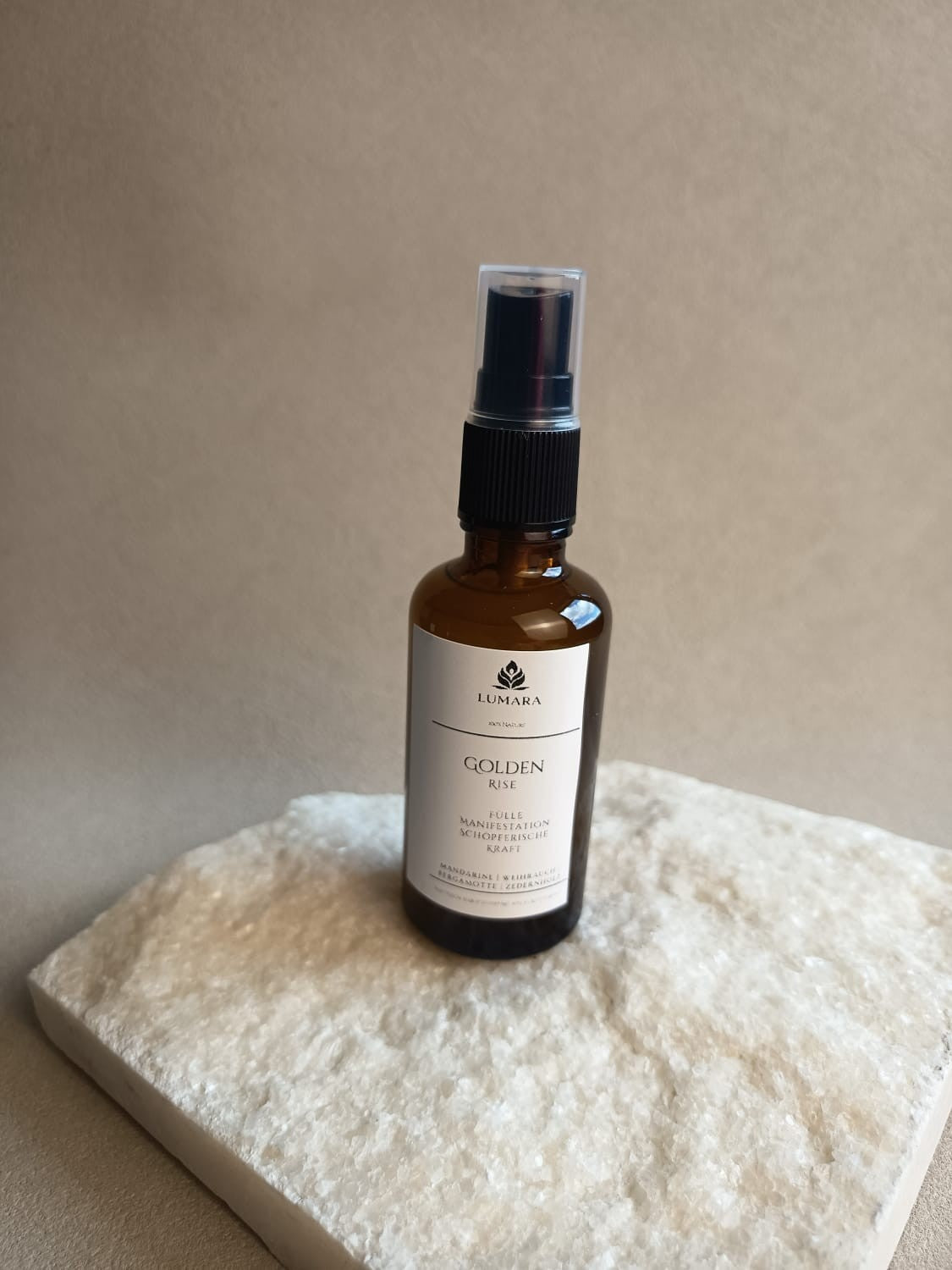 LUMARA Golden Rise Beltane Aura Spray in Amber Glasflasche auf hellem Stein dekoriert
