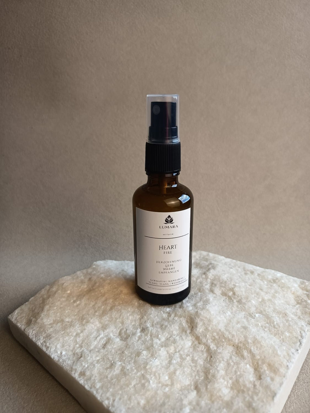 LUMARA Heart Fire Beltane Aura Spray in Amber Glasflasche auf hellem Stein dekoriert
