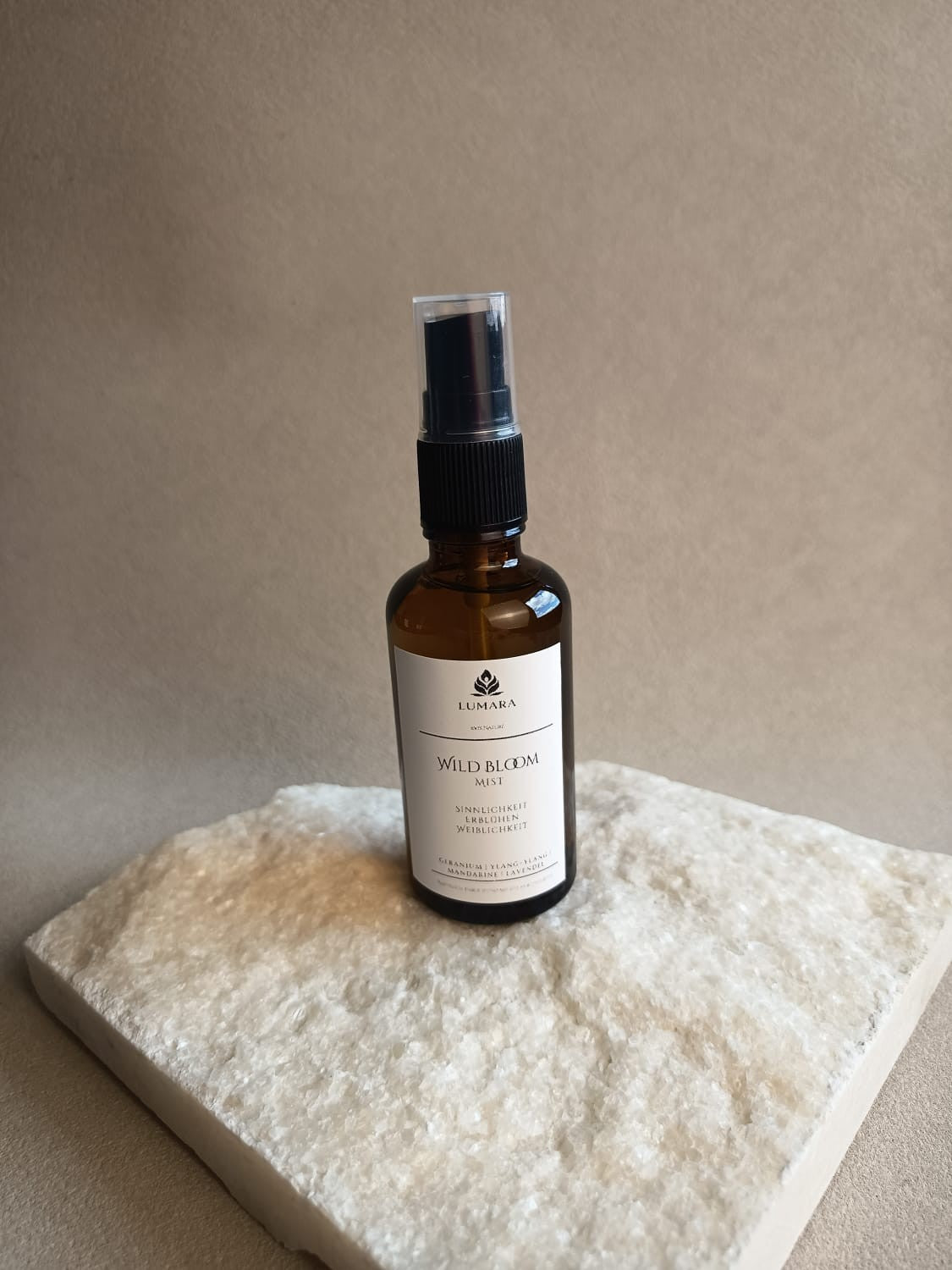 LUMARA Wild Bloom Beltane Aura Spray in Amber Glasflasche auf hellem Stein dekoriert